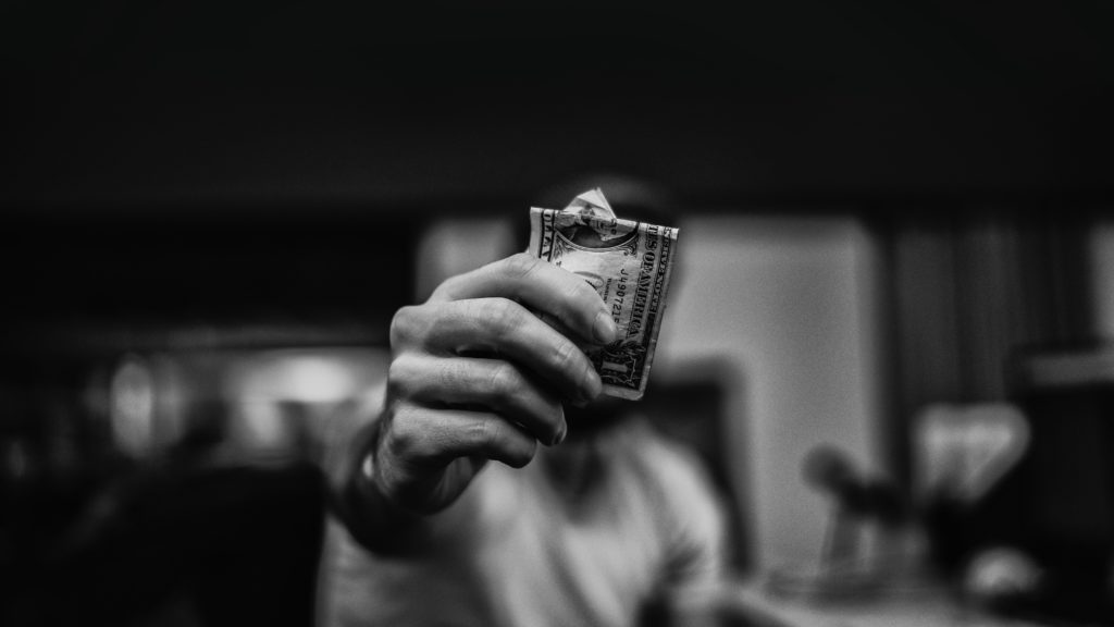 A black and white photo of a hand holding dollar bills.