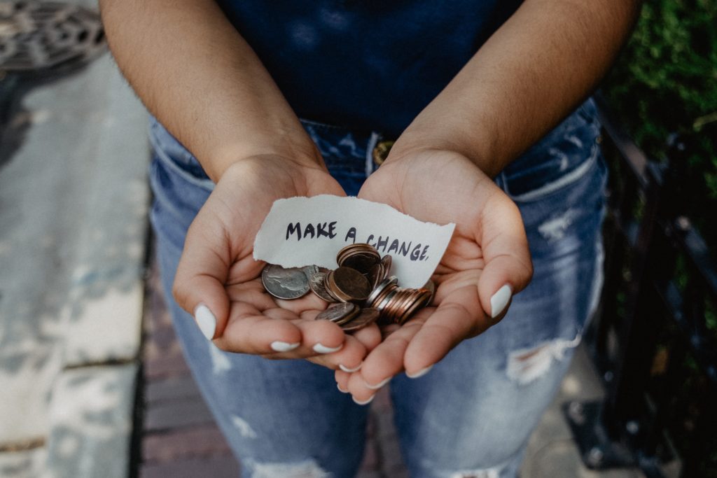 Hands holding coins with a note that says "make a change." This image is represents the need to make a gift for or donate to persecuted Christians in China.