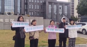 Family members holding signs outside the court, hoping to attend the trial